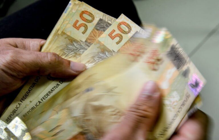 mao segurando moedas e notas fiscais